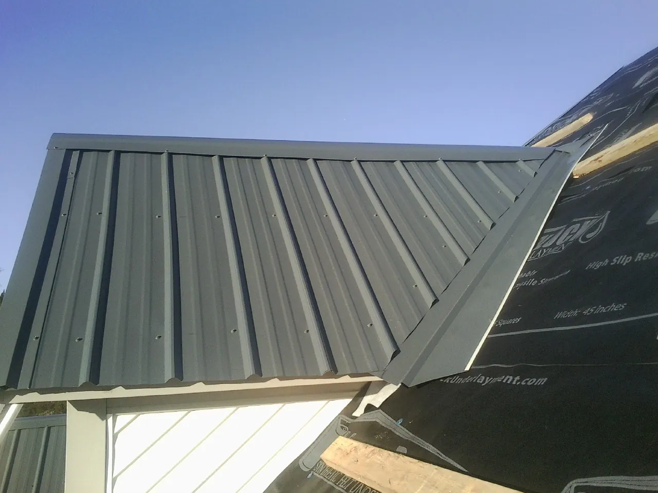 Gray metal roof panels going on over a garage gable in Alvada