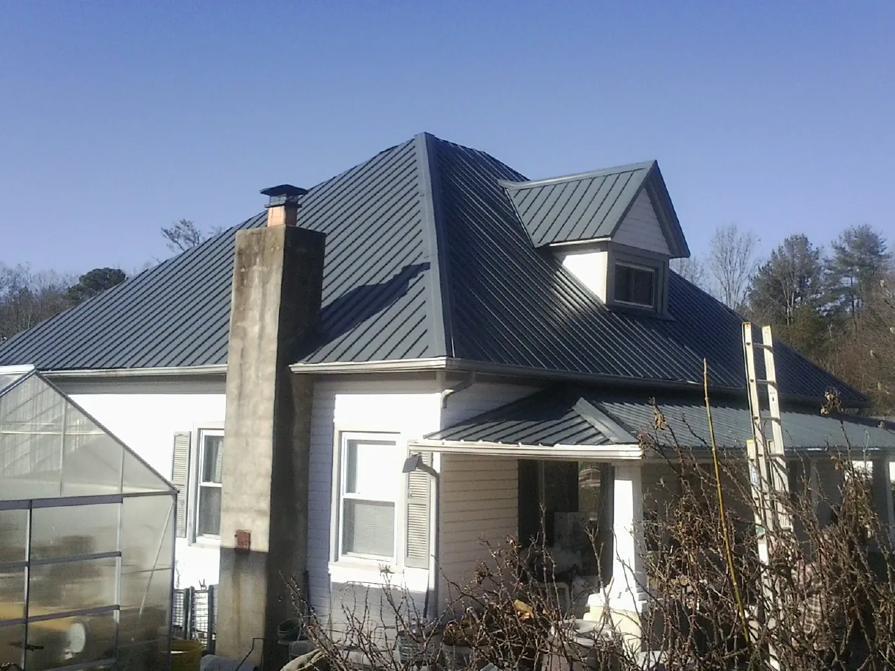 Dark blue standing seam metal roof on a white farmhouse with dormer — Slate & Tile Roof Repair by Roofing Brothers in Alvada
