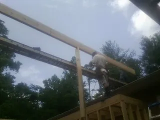Carpenter setting a ridge beam over a new addition frame — Ice Dam Removal by Roofing Brothers in Alvada