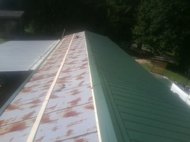 Old rusted panels beside newly installed green metal roofing — Wind Damage Roof Repair by Roofing Brothers in Alvada