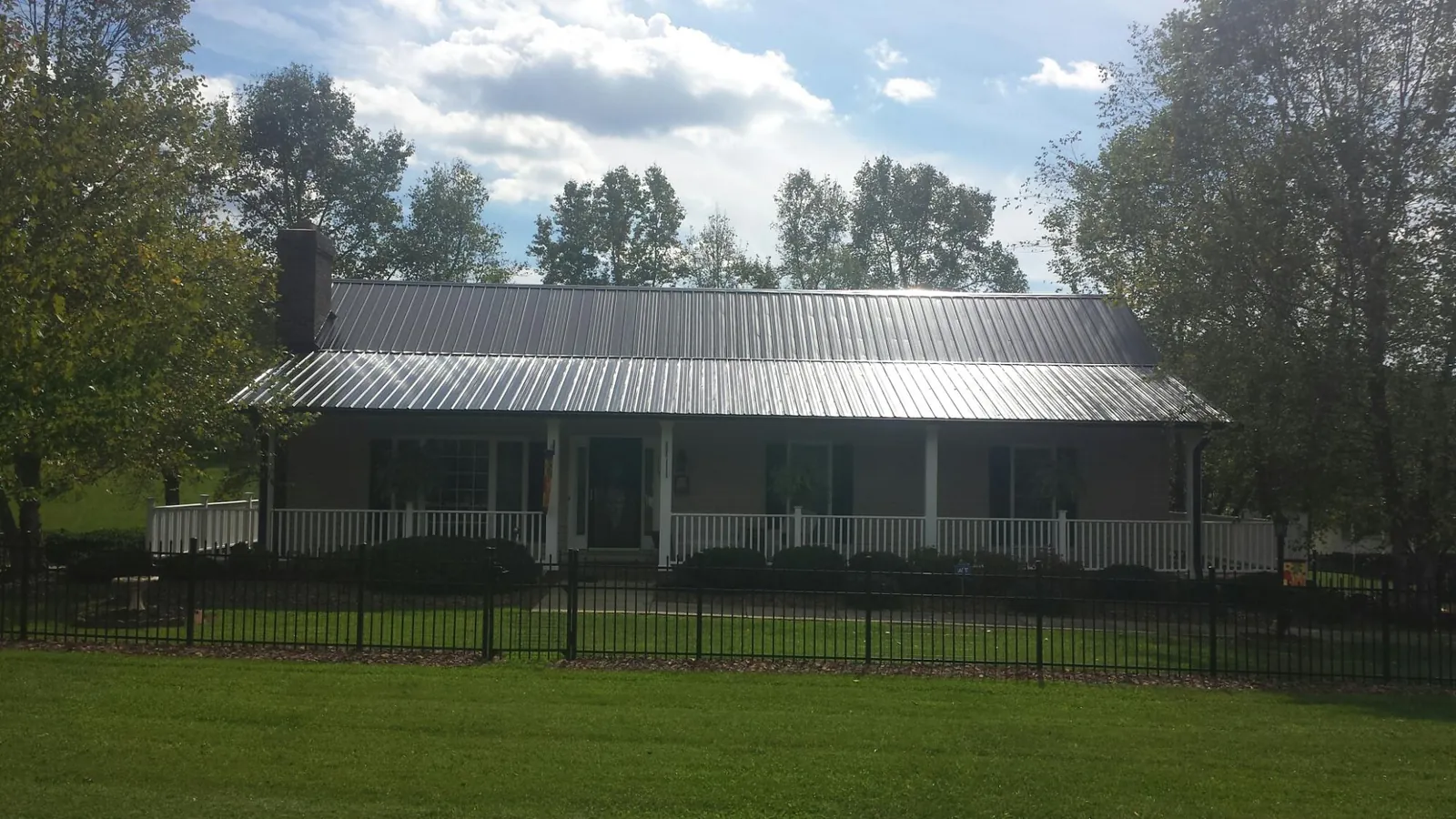 Gray metal roof on a brick ranch with a full width front porch — Gutter Guard Installation work by our crew in Alvada