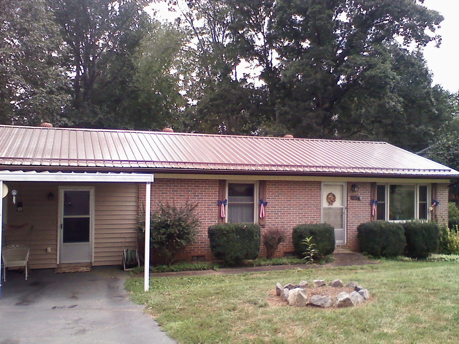 Bronze metal roof and carport on a brick ranch home — Roof Repair work by our crew in Alvada