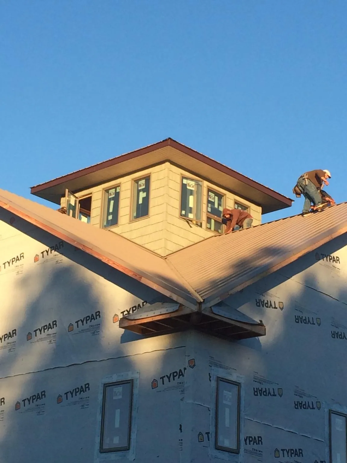 Roofers working around a rooftop cupola on a new metal roof at sunset — Roof Waterproofing in Alvada by Roofing Brothers
